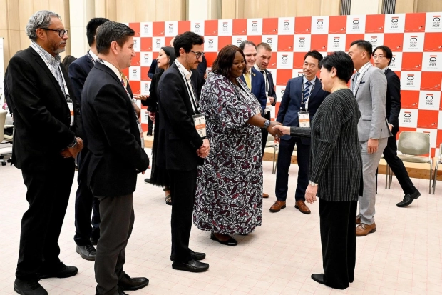 両都市の職員に囲まれて握手するカマラ氏と小池百合子都知事