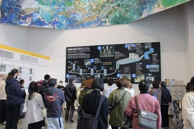 巨大パネルの前で首都圏外郭放水路を説明