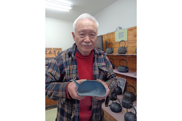 厚さ約2ミリと薄くて軽い薫山工房の鉄瓶の模型を手にする佐々木さん。「手作りだからこそ、この薄さで作れます」と言う