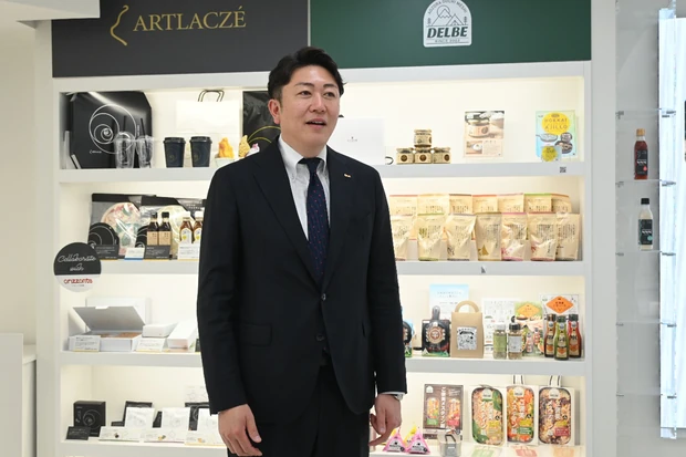 自社ブランドの商品を前に抱負を語る牧野克彦社長（アイビック食品本社で）