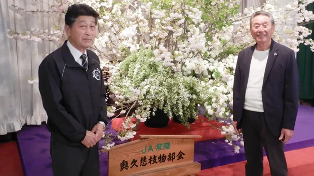 総会会場の装飾を背に石川会長（右）と長山豊明部会長