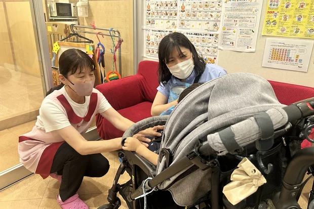 子どもの園での様子について笑顔で話す保護者とテトテひらおの保育士